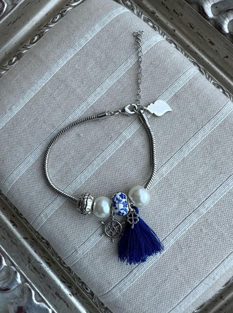 bracelet argenté fantaisie avec des breloques représentant les azulejos portugais ainsi que le Cœur de Viana, mais également avec des perles et 1 pompon bleu.