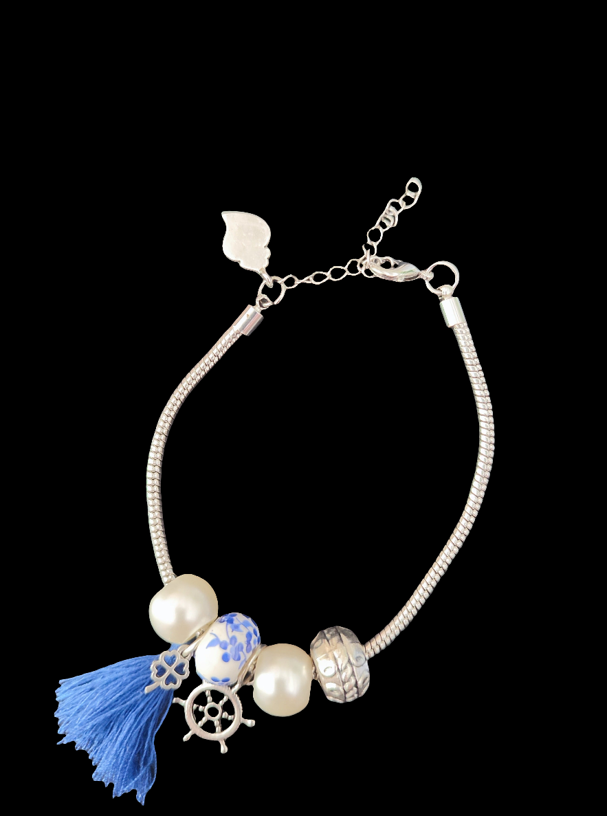 bracelet argenté fantaisie avec des breloques représentant les azulejos portugais ainsi que le Cœur de Viana, mais également avec des perles et 1 pompon bleu.